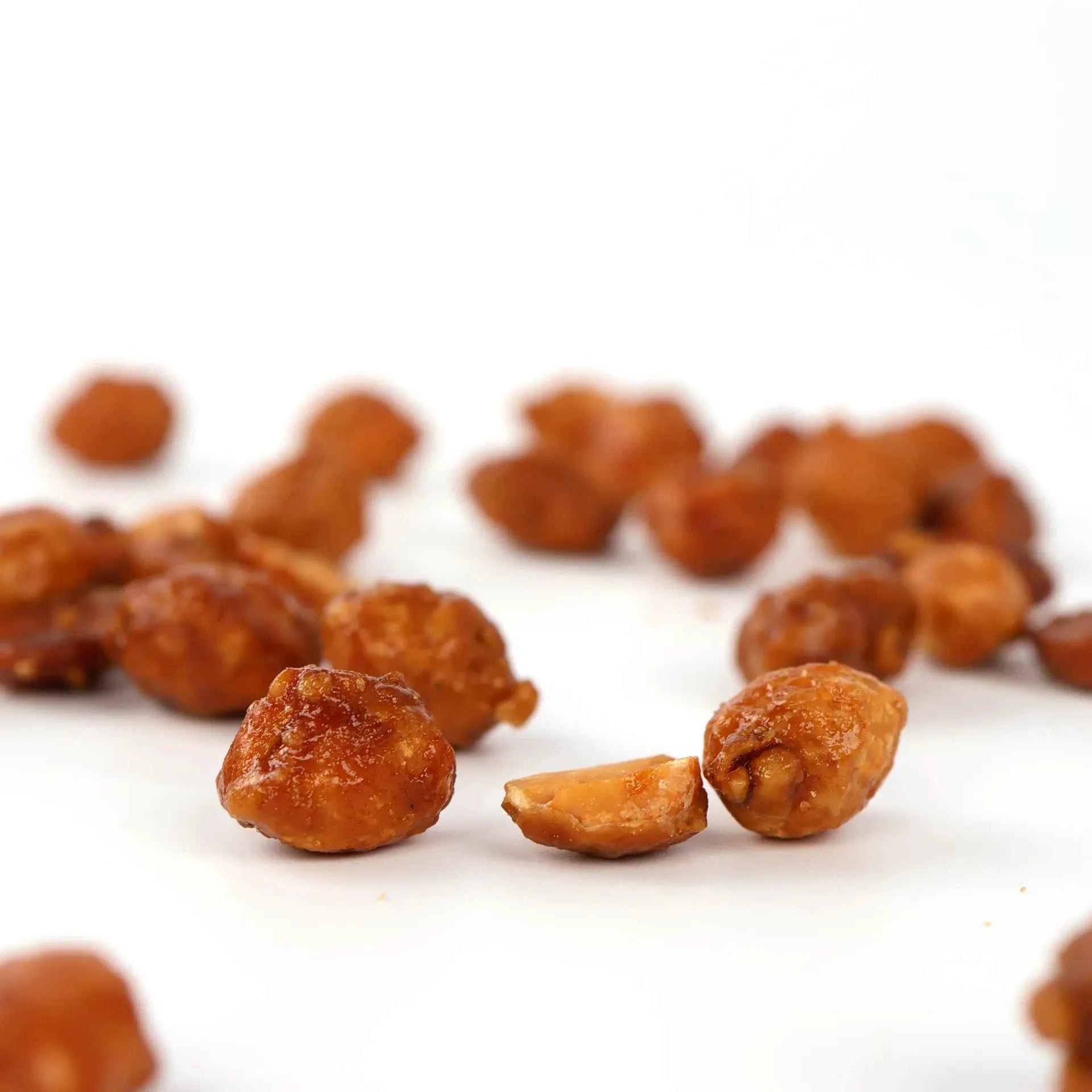 Cacahuètes caramélisées étalées sur une surface blanche.
