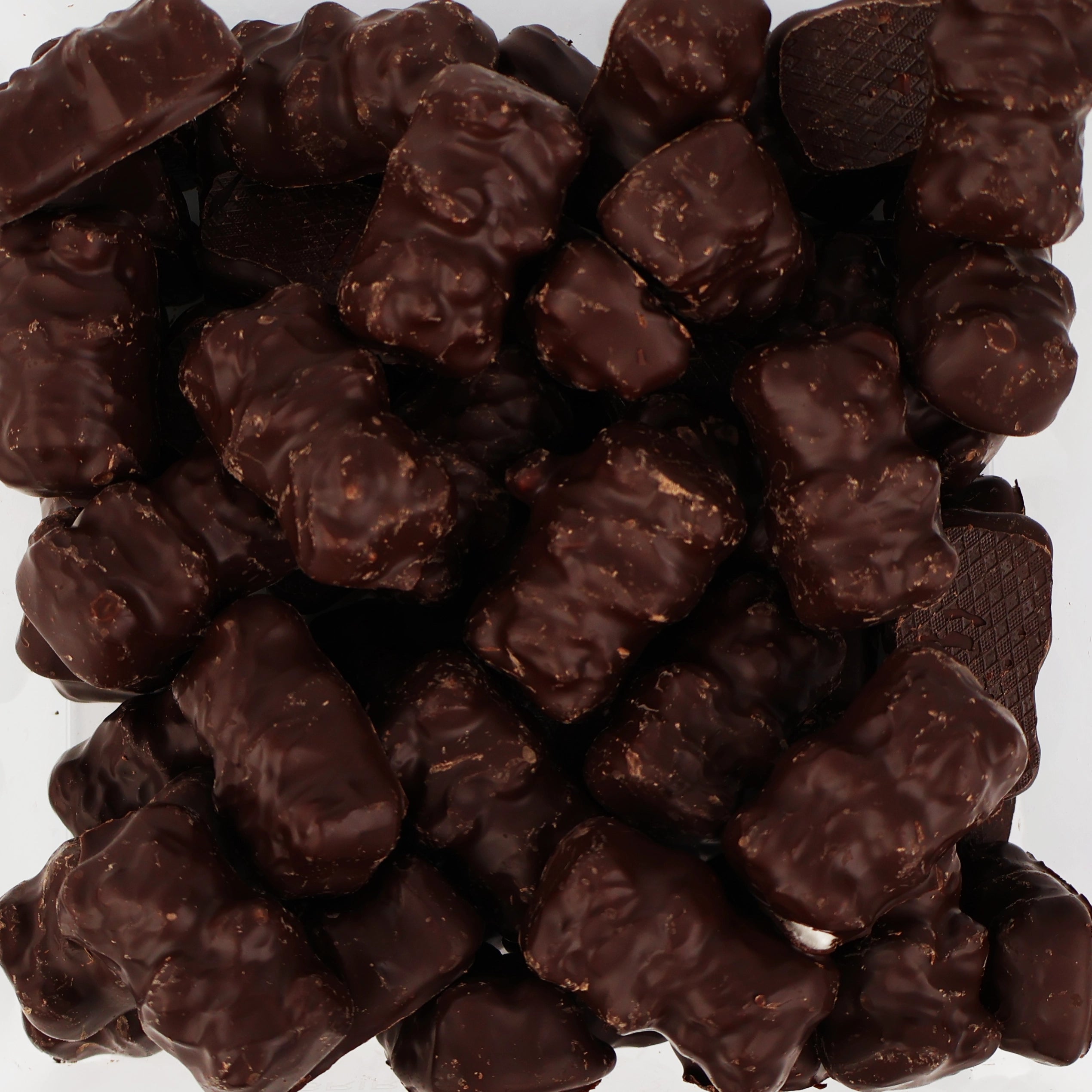 Gros plan sur un tas de bonbons oursons en guimauve recouverts de chocolat noir.