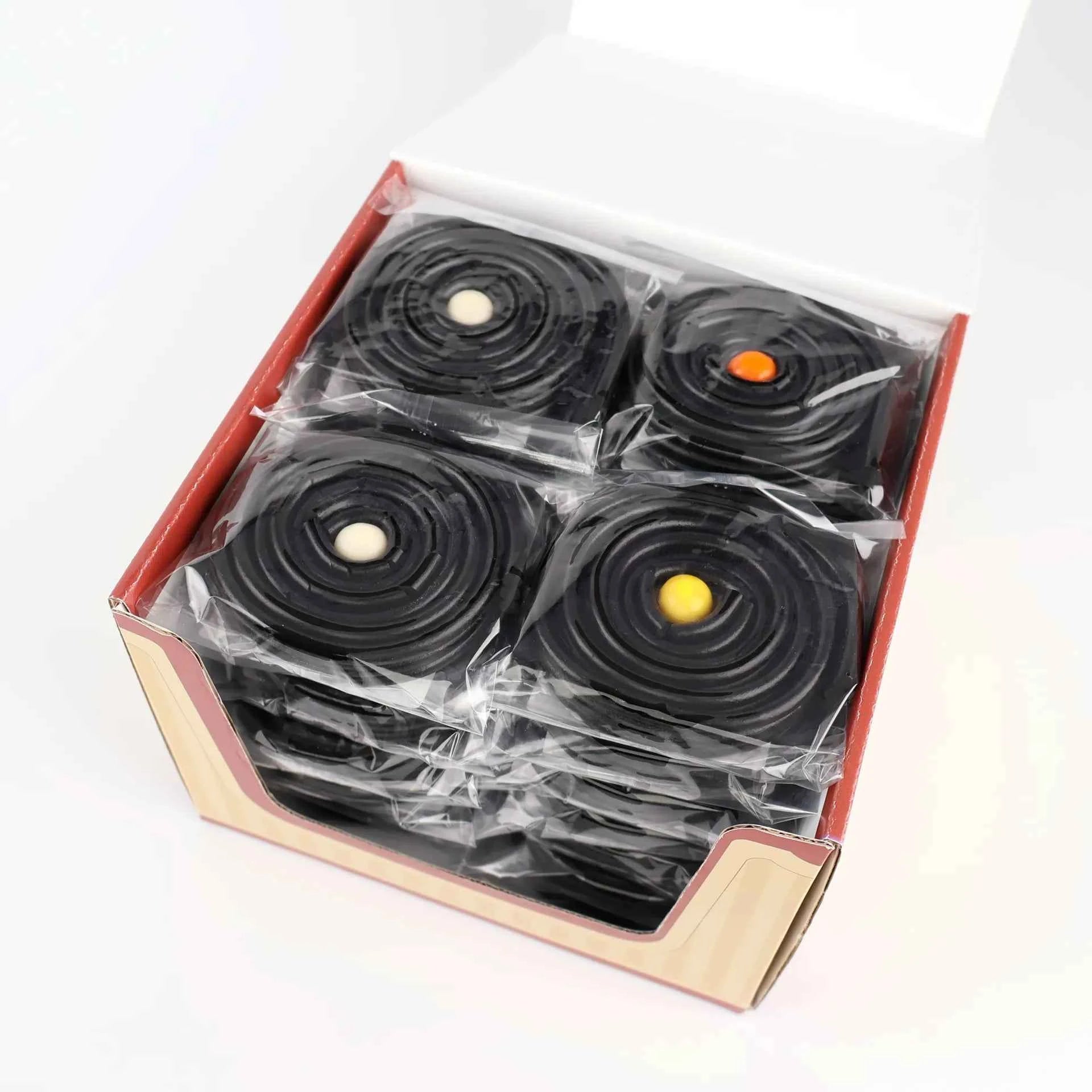 Vue de dessus de rouleaux de réglisse emballés individuellement dans leur boîte.