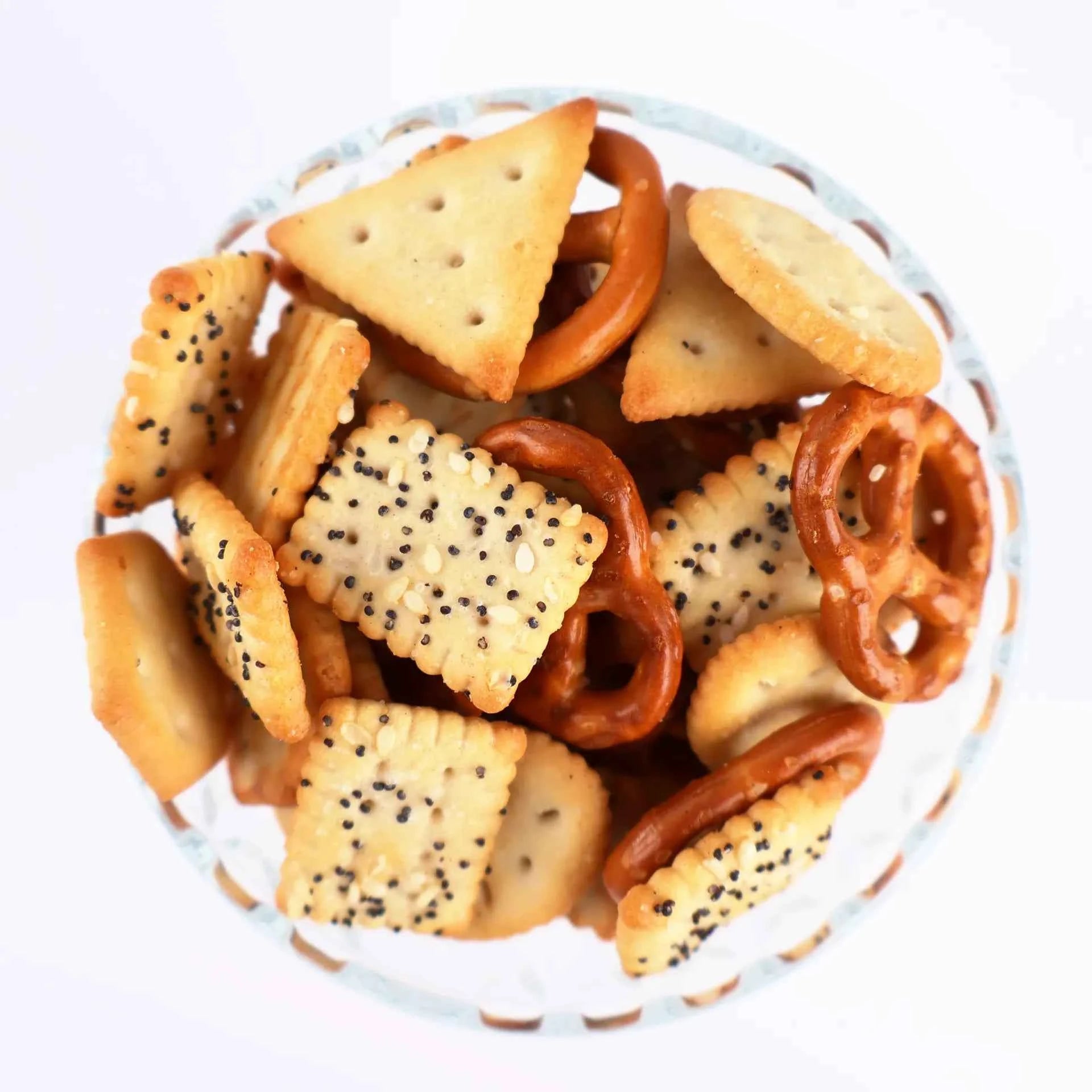 Bol en verre rempli de mélange salé Croco composé de bretzels et de crackers aux graines de pavot.