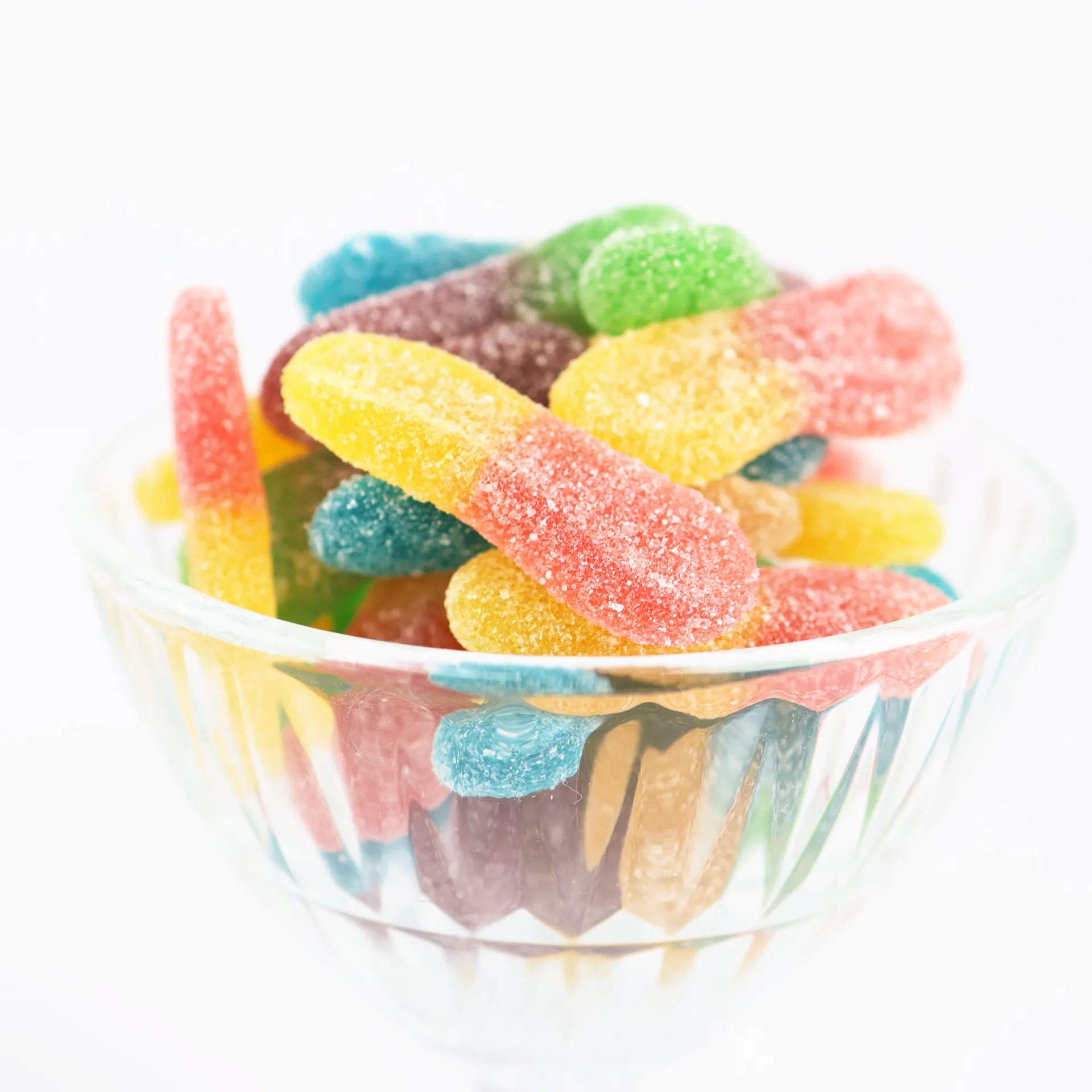 Coupe en verre remplie de langues acides colorées saupoudrées de sucre.