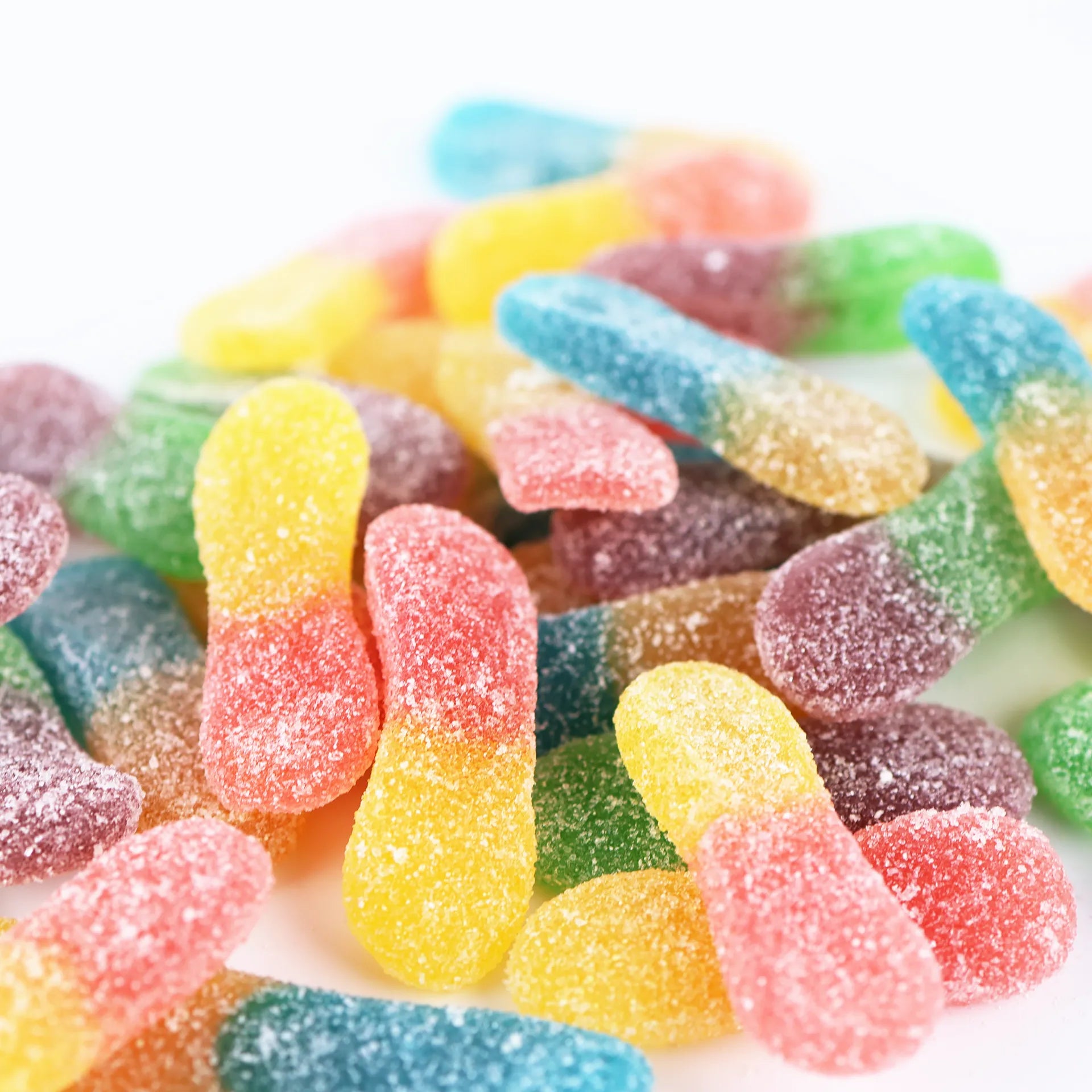 Accumulation de bonbons langues acides aux couleurs vives : bleu, vert, jaune et rouge.