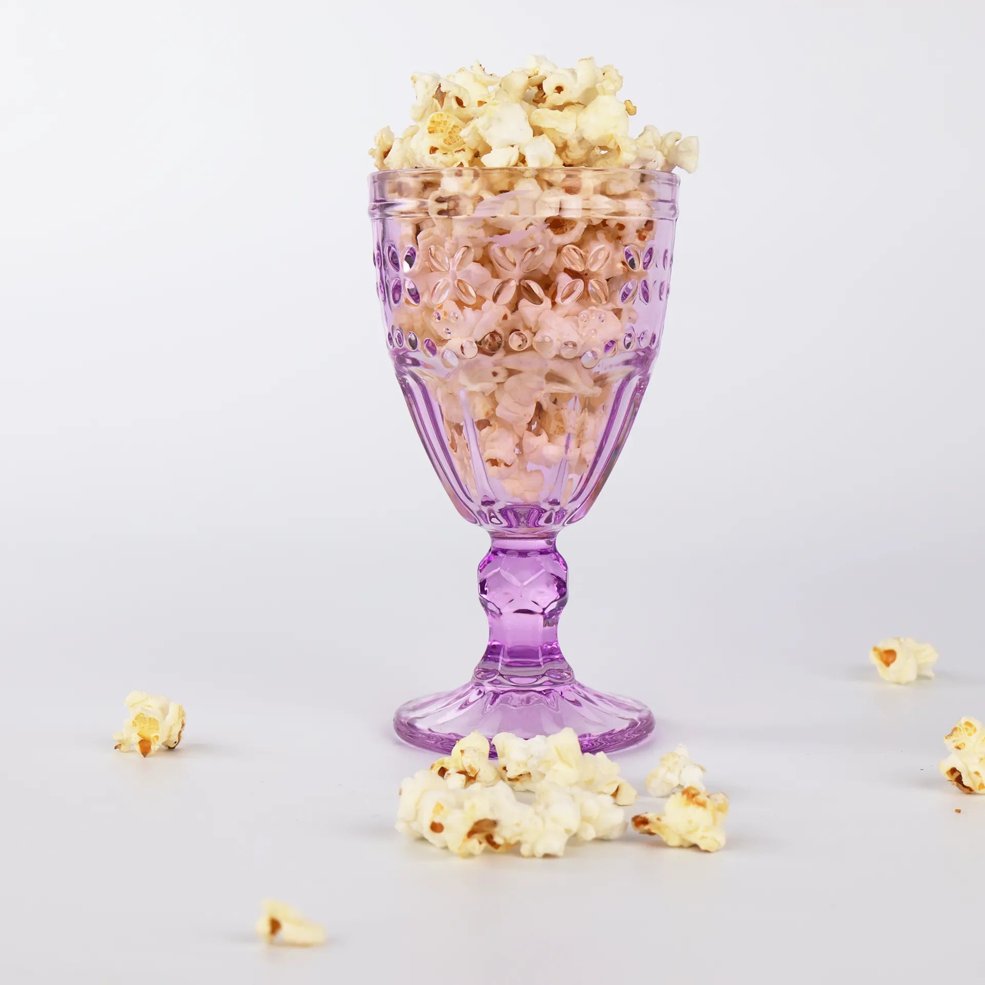 Présentation élégante de pop-corn sucré dans une coupe en verre mauve.